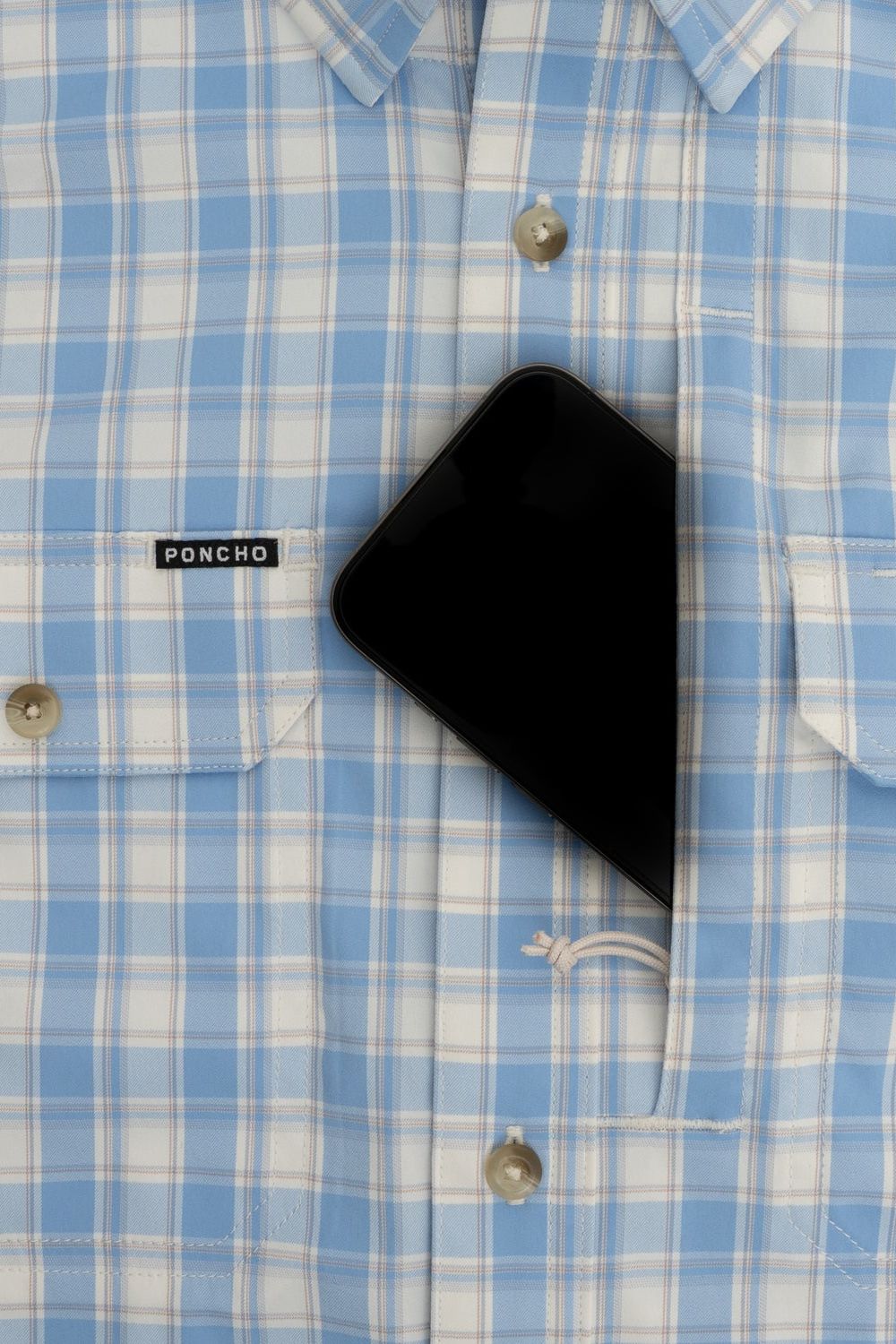 A close-up of a light blue and white plaid button-down shirt with a black smartphone tucked into the chest pocket. The brand label 'PONCHO' is visible on the pocket.