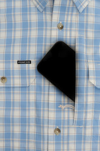 A close-up of a light blue and white plaid button-down shirt with a black smartphone tucked into the chest pocket. The brand label 'PONCHO' is visible on the pocket.