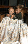 Two kids hugging wrapped up in an Aztec printed sherpa blanket 
