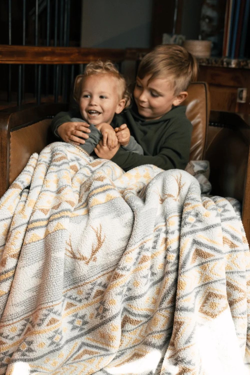 Two kids hugging wrapped up in an Aztec printed sherpa blanket 