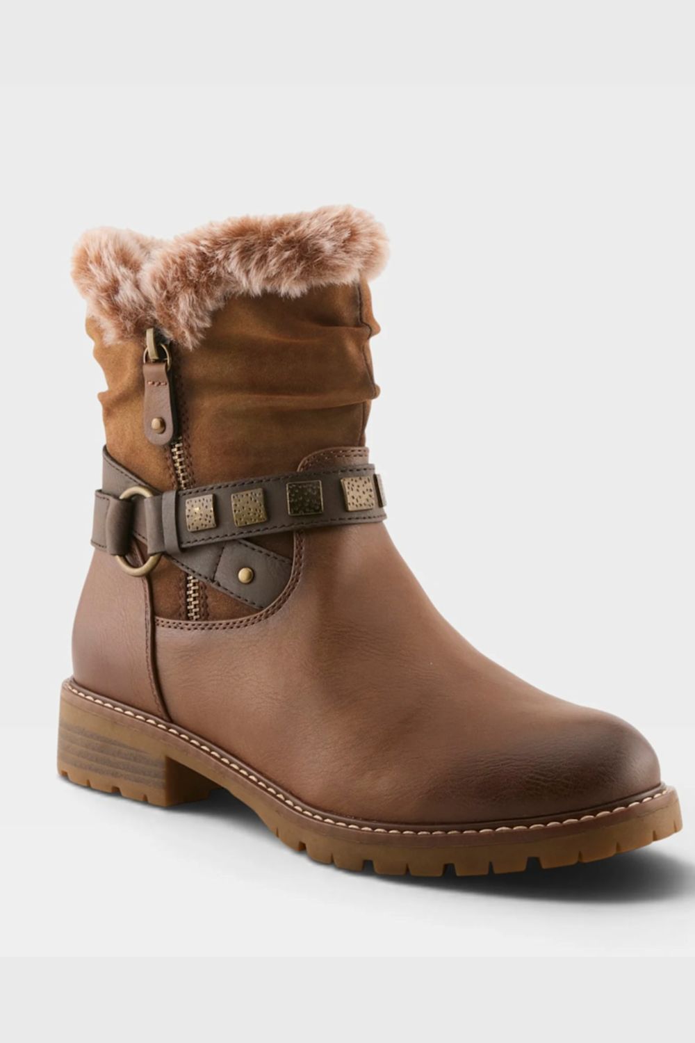 A brown leather ankle boot with a faux-fur collar, a decorative strap with studs and a buckle around the ankle, and a low block heel, shown on a light gray background.