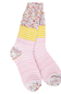 A pair of multicolor patterned crew socks with distinct sections: a multicolor variegated top, a yellow band with white floral motifs, and a light pink lower section with white floral and stripe patterns.