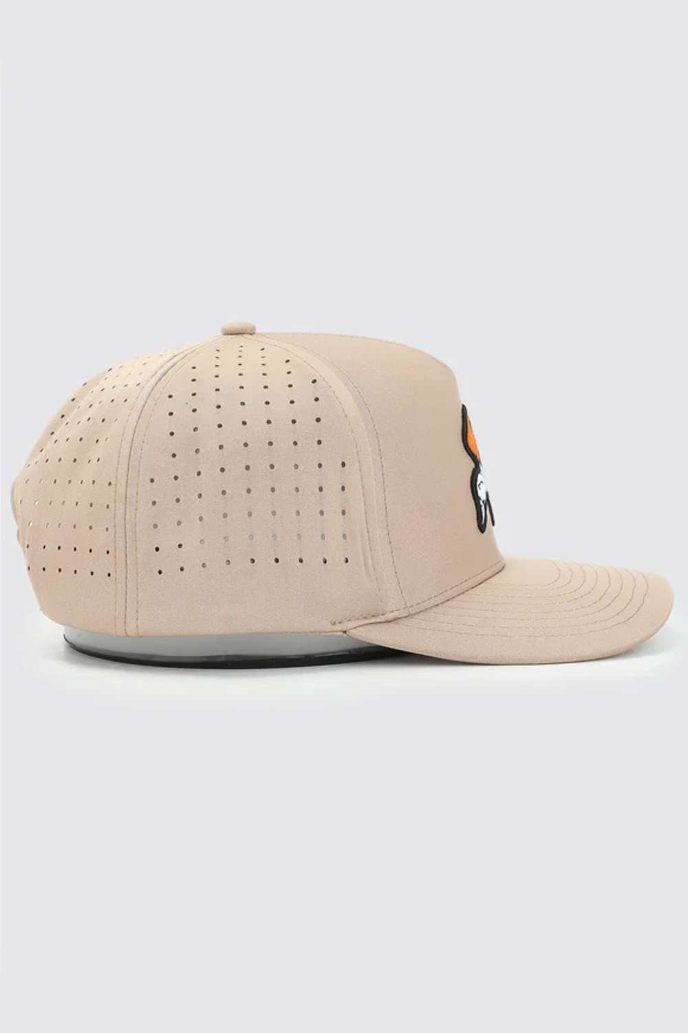 A light beige baseball cap with perforated panels on the front and a small black and orange graphic on the side, shown against a light gray background.