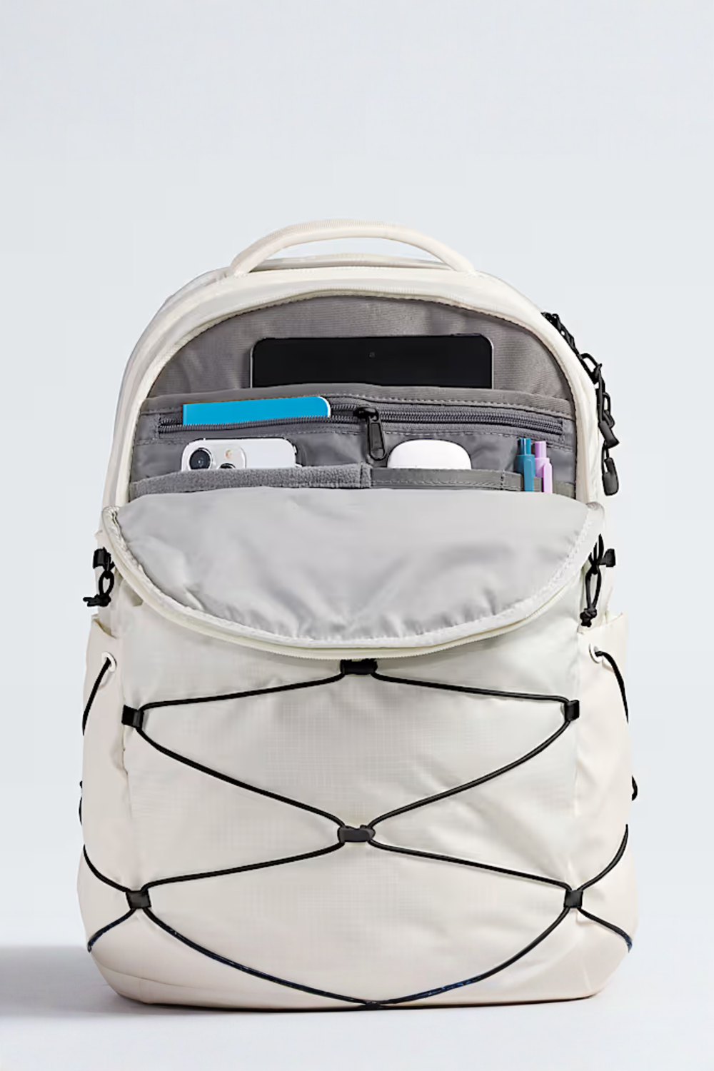 White backpack with open front pocket showing organized items on a light gray background