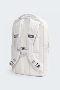 A white backpack shown from the back, featuring padded shoulder straps, a central buckle strap, a top carry handle, and a small black The North Face logo patch on the upper back, set against a light gray background.