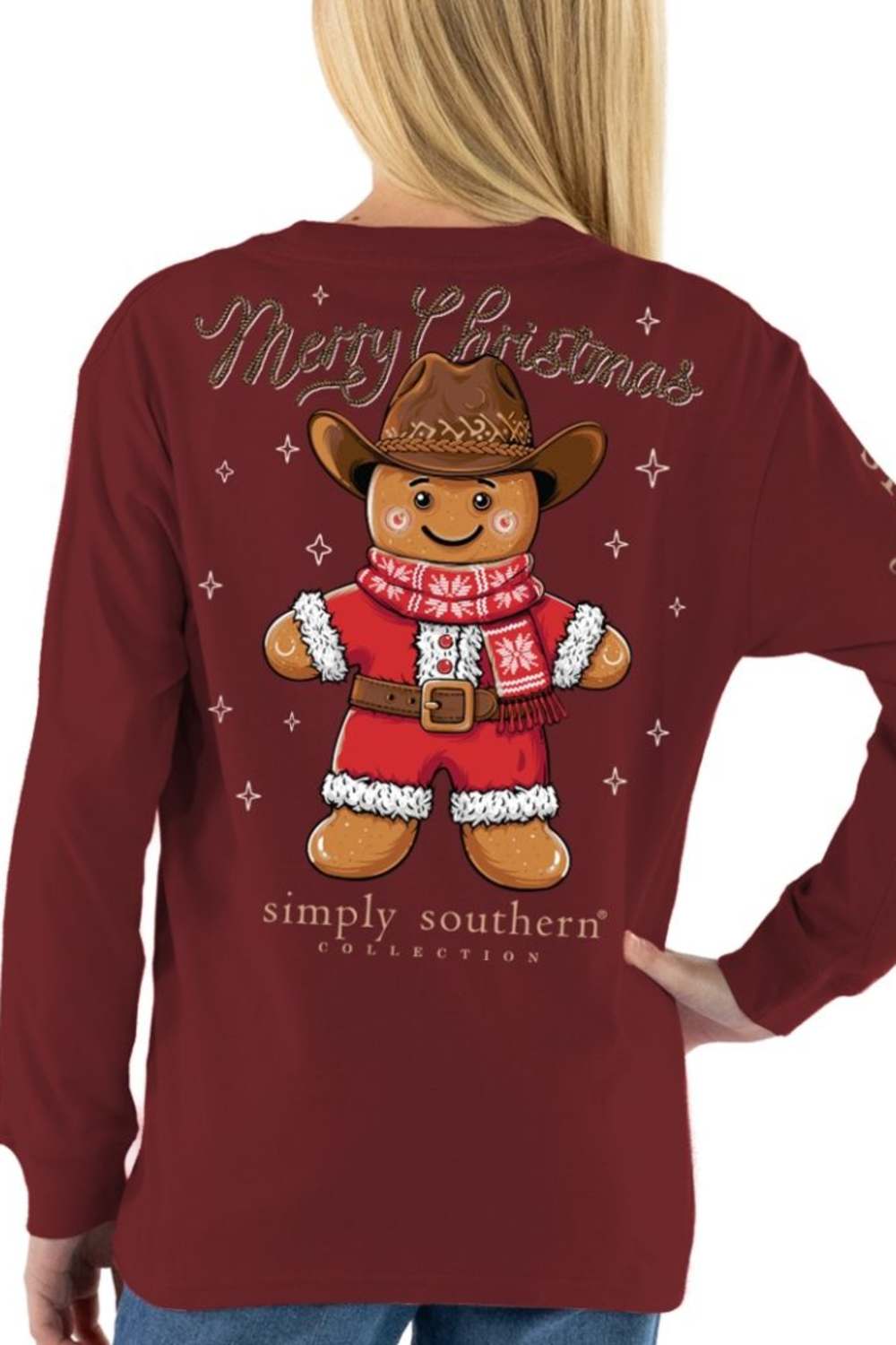 A woman wearing a maroon long-sleeve shirt from the back, featuring a large graphic of a gingerbread man dressed as Santa Claus with 'Merry Christmas' text and 'simply southern' branding.