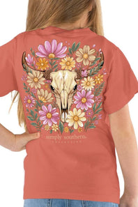 A woman shown from the back wearing a coral short-sleeve t-shirt with a large graphic print of a deer skull surrounded by colorful wildflowers. The brand name 'simply southern' is printed below the graphic.