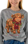 A person wearing a heather gray crewneck sweatshirt featuring a graphic of a brown Scottish Highland cow decorated with Christmas lights and a red plaid scarf, with the text 'simply southern' below.