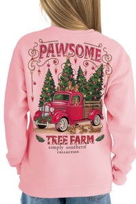 A person wearing a light pink crewneck sweatshirt, shown from the back. The sweatshirt features a large graphic print of a red vintage truck carrying Christmas trees, with the text 'PAWSOME' and 'TREE FARM simply southern COLLECTION'.