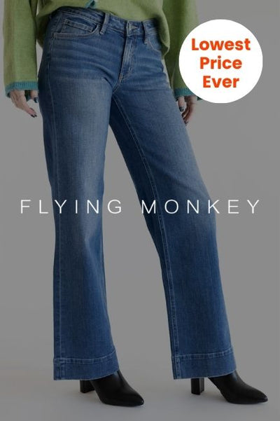 A person wearing mid-waisted, dark-wash wide leg jeans and black boots. The white text FLYING MONKEY is centered across the legs, and a white circular badge in the top-right corner reads Lowest Price Ever in orange text