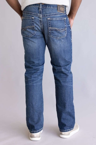 Back view of a model wearing medium-wash straight-leg jeans with stitched back pockets, paired with a white sweater and white sneakers against a neutral gray background.