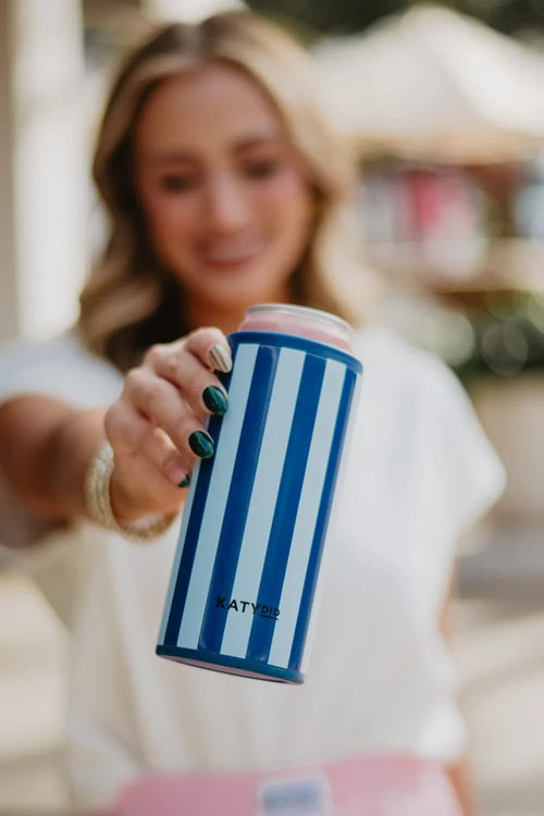 A woman holding a blue and white striped can cooler with the brand name 'KATYD' visible on the front, set against a blurred outdoor background.
