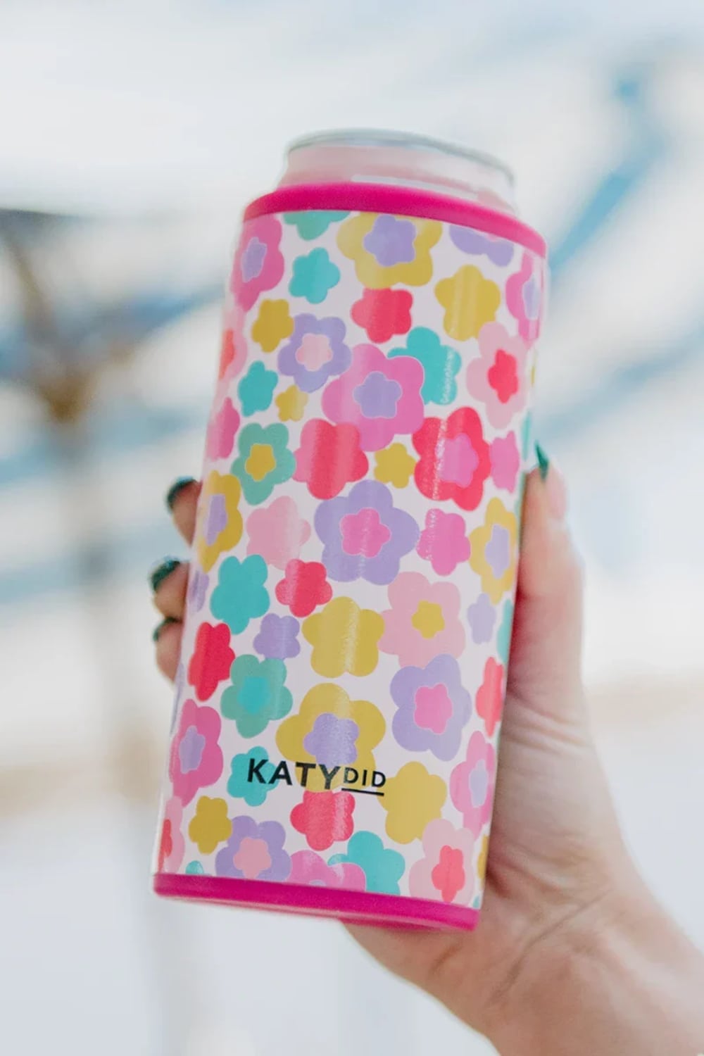 A can cooler with a colorful floral pattern in pink, yellow, teal, and purple, featuring the brand name KATYDID near the bottom.