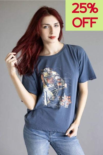 Woman wearing a navy blue graphic t-shirt on a plain background and a 25% off callout in the upper right hand corner of the image