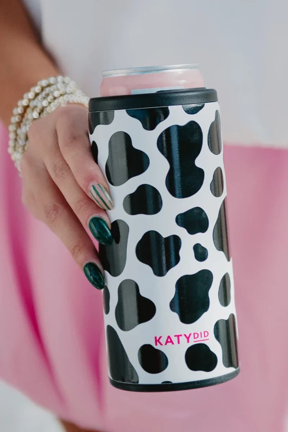 Hand holding a can with a black and white cow print design and 'KATYDID' branding.