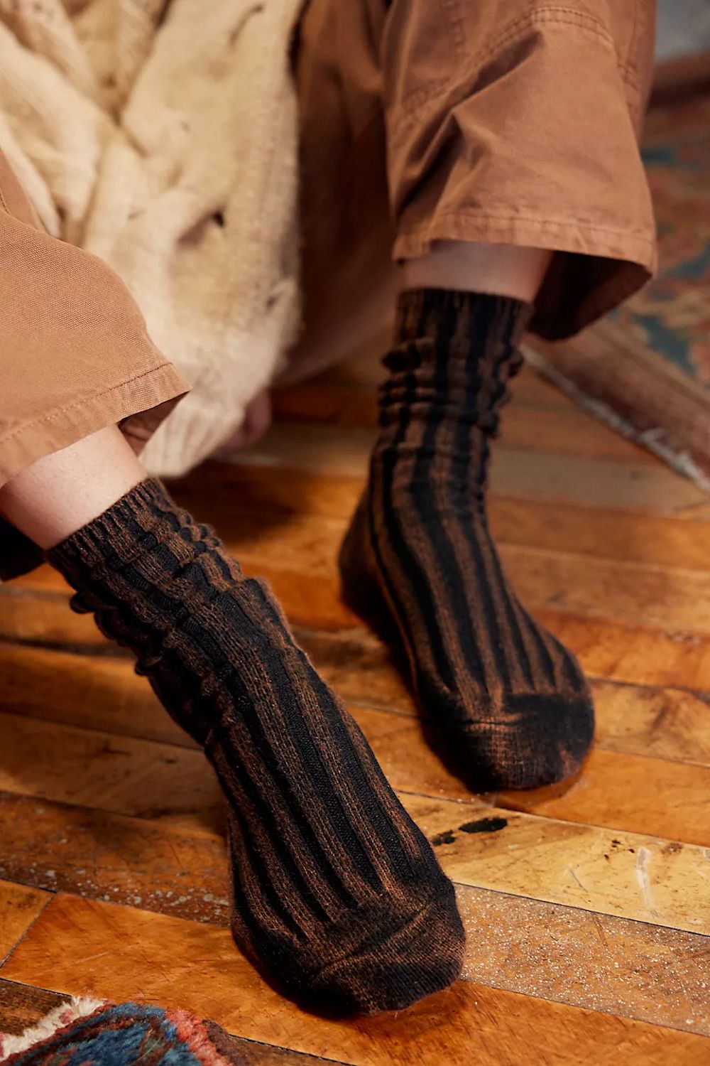 Person wearing brown ribbed socks on a wooden floor