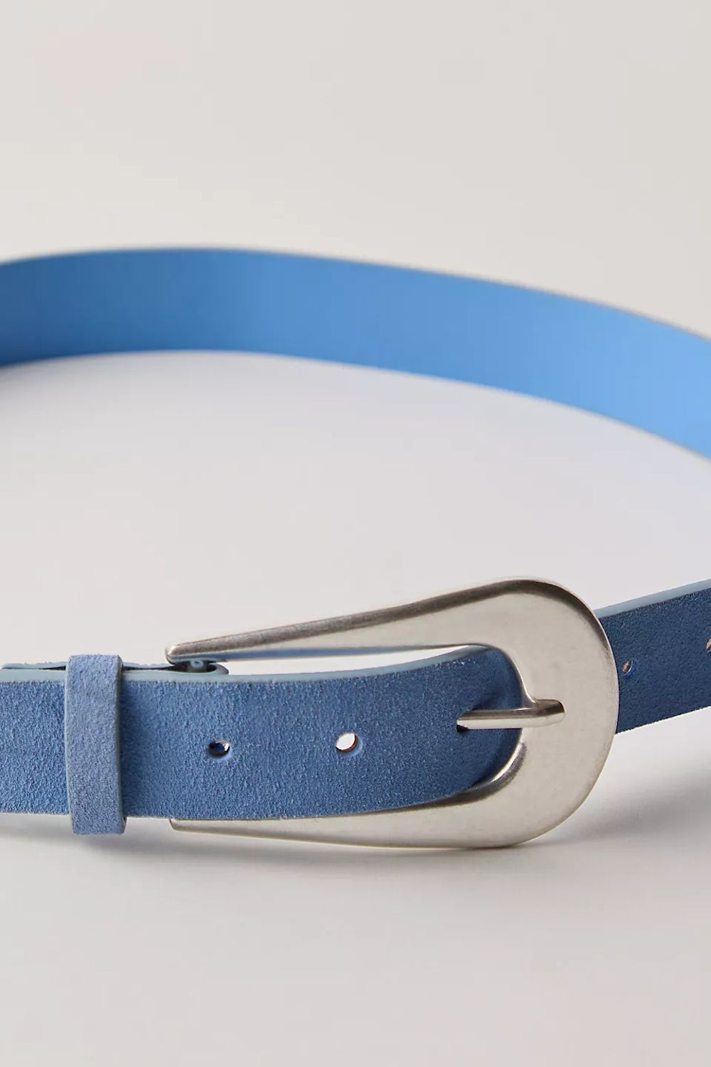 A close-up of a blue leather belt with a polished silver-tone metal buckle, shown on a light gray background.