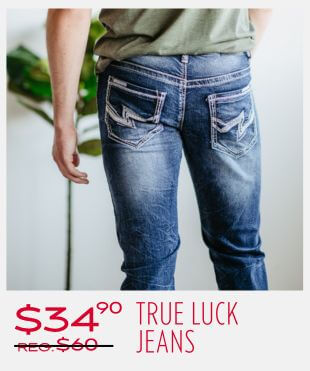 Person wearing blue denim jeans with facing the wall behind them with a small tree in the background with a promotional banner at the bottom that reads '$34.90 Reg $60 stikethrough True Luck Jeans'