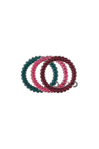Three beaded stretch hair ties stacked together on a white background, featuring glossy dark teal, translucent pink with silver flecks, and deep burgundy beads.