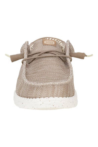 A single slip-on shoe with a textured beige woven upper, matching beige laces, and a speckled white sole, shown from a front-facing perspective on a white background.