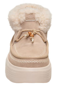 A beige suede slip-on boot with a thick cream platform sole, a fluffy cream shearling collar, and decorative tan and cream laces, shown from a front-facing angle on a white background.