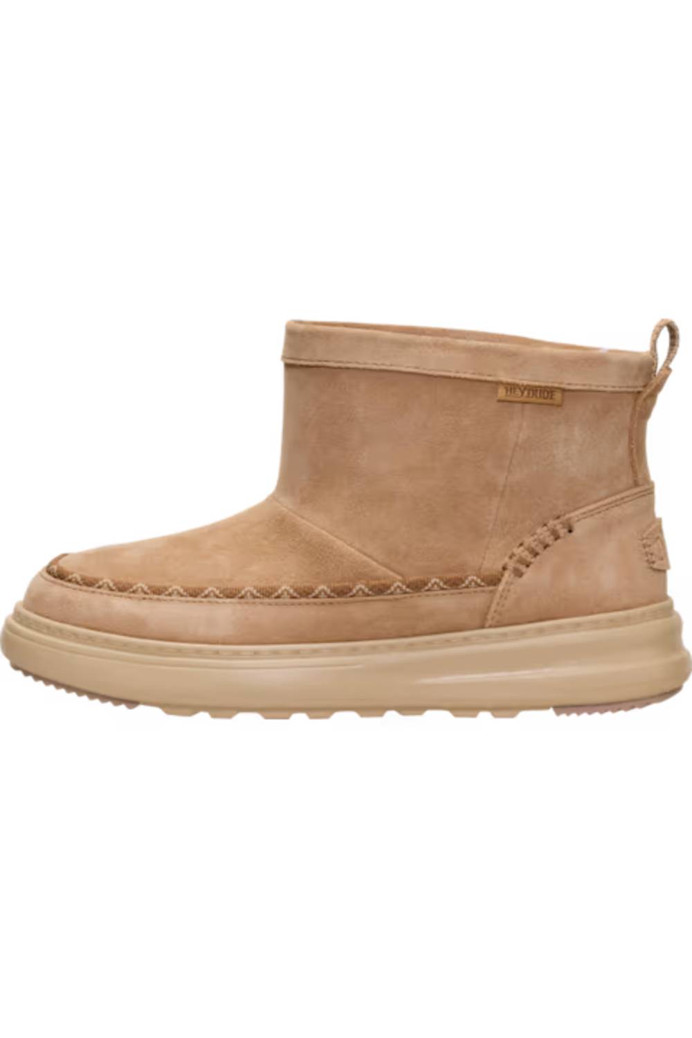 A light tan suede ankle boot with a thick beige sole, featuring decorative stitching along the vamp and a small pull tab on the heel.