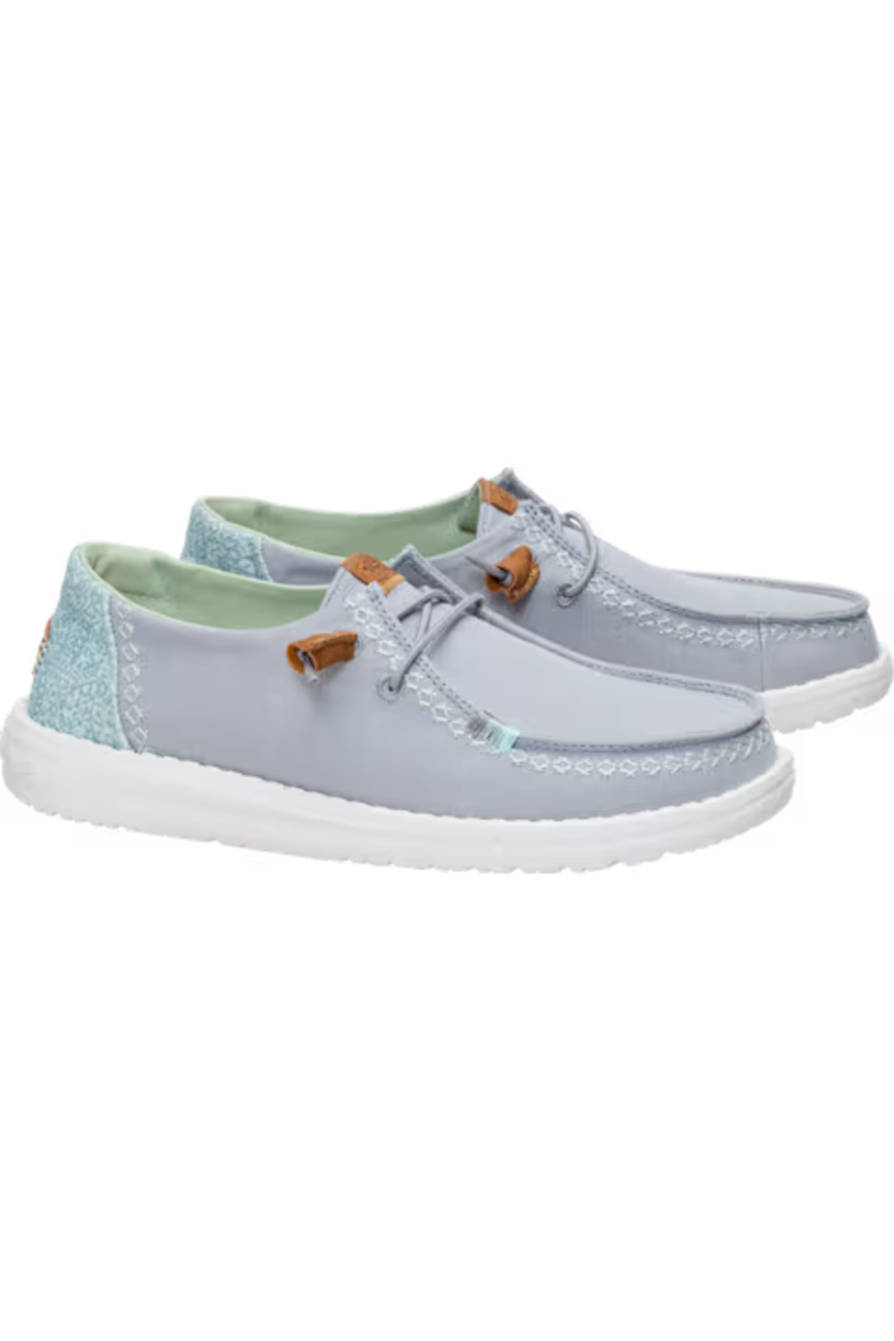 A pair of light blue boat shoes with white soles, featuring a light blue suede upper, a textured glittery light blue heel tab, and small brown leather accents near the eyelets.