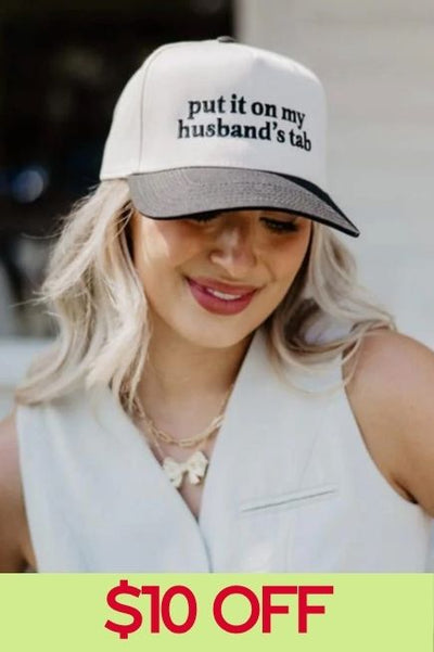 Woman wearing a cream and black colored trucker hat with text that reads 