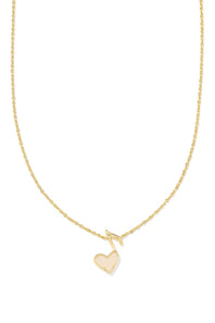 A delicate gold chain necklace featuring a small gold heart pendant with a textured, glittery gold outline and a gold musical note charm above it, set against a plain white background.