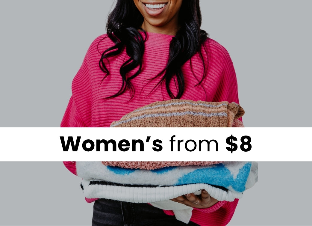 A woman wearing a hot pink ribbed knit sweater holding a stack of different sweaters. The image has a dark overlay with a white stripe in the image with text that reads Women's from $8