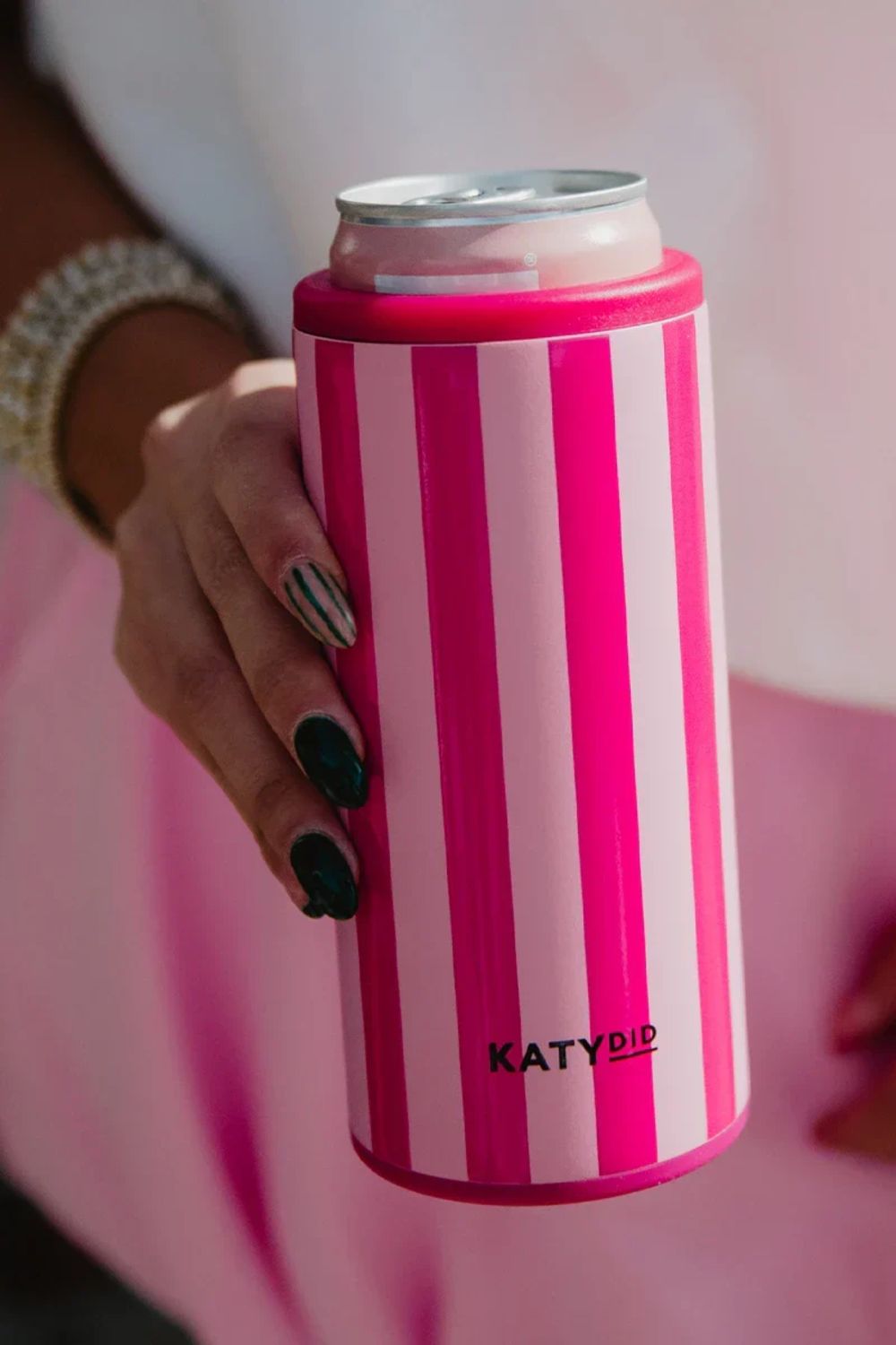 Hand holding a pink and white striped can cooler with 'KATYDID' branding.