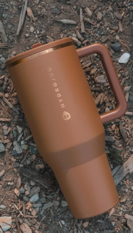 Brown HydroJug branded tumbler laying in dirt