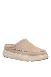 A single slip-on clog-style shoe in light beige suede with a decorative stitched border and a thick cream-colored sole, shown against a plain white background.