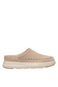 A single slip-on clog-style shoe in a light beige suede-like material with a thick cream sole and a decorative stitched detail across the vamp, shown against a plain white background.