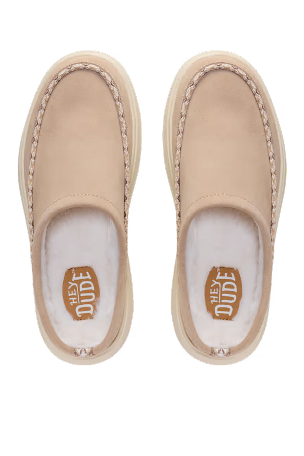 A pair of beige slip-on moccasin-style slippers with white faux-fur lining and a tan insole featuring the HEY DUDE brand logo, shown from a top-down view on a white background.