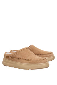 A pair of tan suede slip-on clogs with thick beige platform soles and decorative stitching, shown against a plain white background.