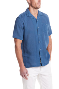 Weatherproof Vintage Cotton Airtex Shirt for Men in Blue Ashes; Man wearing a blue short-sleeve button-up shirt with white pants on a white background