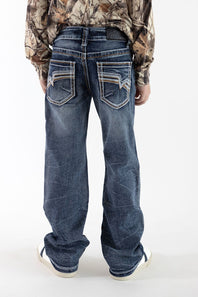 A boy viewed from the back wearing dark wash denim jean with detailed stitching on the back pockets, a long sleeve camo shirt, and white sneakers in front of a white studio background