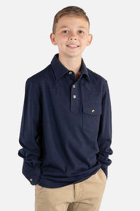 A young boy wearing a navy blue long-sleeve button-up shirt with a chest pocket and khaki pants, standing against a light gray background.