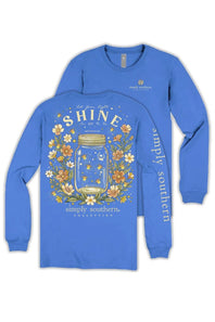 A royal blue long-sleeve t-shirt shown from both the front and back. The front features a large graphic of a glass mason jar filled with stars, surrounded by yellow, orange, and white wildflowers, with the text 'SHINE' and 'simply southern, COLLECTIONS' below.