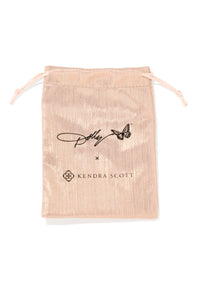 A metallic blush pink drawstring pouch featuring a black printed signature and the Kendra Scott logo, set against a plain white background.