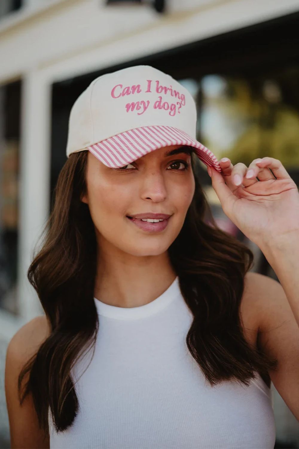 Woman wearing a cap with text, standing outdoors.