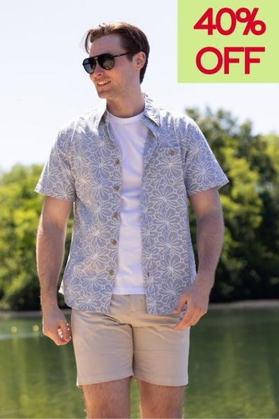 Man wearing a floral button up open with tan shorts, a basic white t-shirt and black sunglasses in front of the outdoor setting with a 40% off callout in the upper right corner of the image